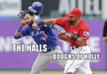 two baseball players are fighting on a field with the words the halls boughs of holly on the bottom .