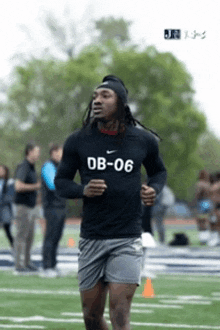 a man wearing a shirt that says db-06 is running on a football field