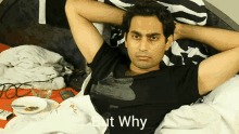 a man in a black shirt is laying on a bed with the words " but why " above him