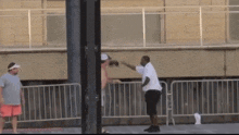 a man in a white shirt and shorts is standing in front of a fence