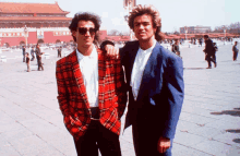 two men are posing for a picture in front of a building with chinese characters on it