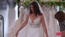 a woman in a wedding dress is standing in front of a display of wedding dresses with a tlc logo in the corner