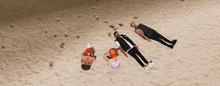 a group of people laying on the sand with one wearing a mask