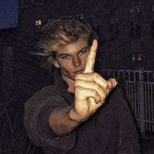 a young man is giving the middle finger in front of a building