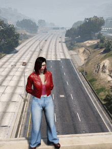 a woman in a red jacket and blue jeans is standing on a bridge overlooking a highway