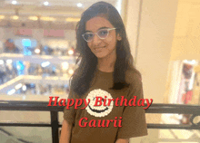 a girl wearing glasses and a brown shirt that says happy birthday gaurii