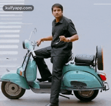 a man in a black shirt is standing on a green scooter .