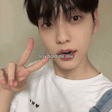 a young man giving a peace sign with the words soy solo de oliv written below him