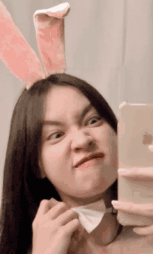 a girl wearing bunny ears takes a selfie with her iphone