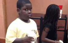 a boy in a yellow shirt is standing next to a girl in a black shirt with the word you on it