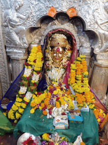 a statue of a woman is surrounded by flowers and a blue box that says ' shree ' on it