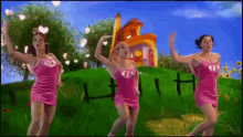 three girls in pink dresses are dancing in front of a house