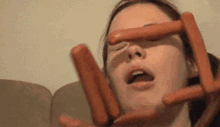 a woman is holding three hot dogs in front of her face .