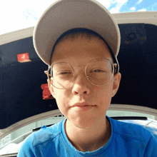 a young boy wearing glasses and a baseball cap looks at the camera