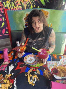 a woman sitting at a table with a margarita in front of a sign that says " viva la lucha "