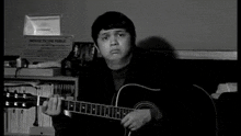 a black and white photo of a man playing a guitar in front of a sign that says notice to the public