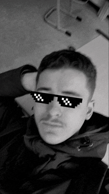 a black and white photo of a young man wearing sunglasses with the letter x on them