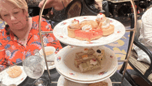 a woman sits at a table looking at a display of desserts