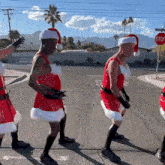 a group of men dressed as santa claus are dancing on a street with a stop sign in the background