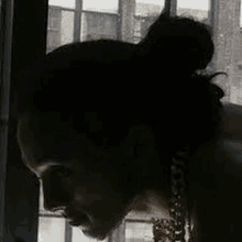 a woman with a bun in her hair is looking out a window .