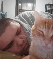 a man laying on a bed with a cat looking at his face