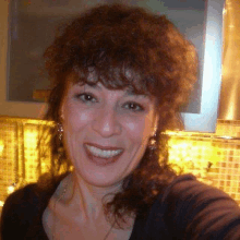 a woman with curly hair is smiling for the camera