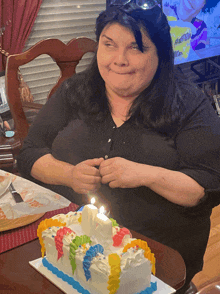 a woman sitting in front of a birthday cake