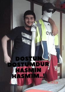 a man standing next to a mannequin with the words " dostun dostumdur hasmin hasmim " on the bottom