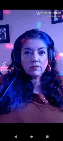 a woman wearing headphones and hoop earrings looks at the camera with a starmaker logo in the corner