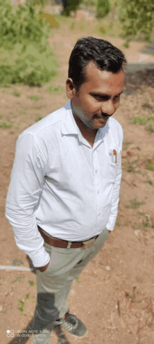 a man in a white shirt is standing in the dirt