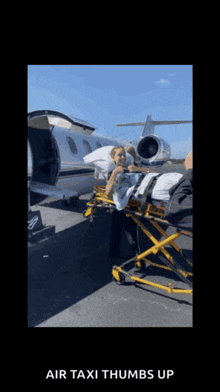 a person on a stretcher in front of an airplane with the words air taxi thumbs up