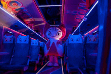 a mascot is standing in the middle of a train with purple lights .