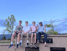 a group of young men sitting on a wall with a sign that says ney