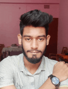 a young man with a beard wears a watch on his left wrist