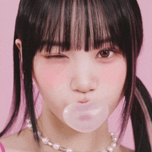 a close up of a girl blowing a bubble with her eyes closed