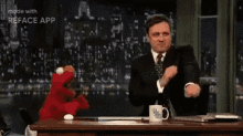 a man in a suit and tie is sitting at a table with a stuffed animal .