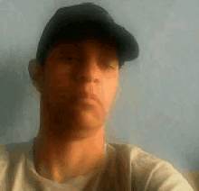 a man wearing a hat and a white shirt is taking a picture of himself .