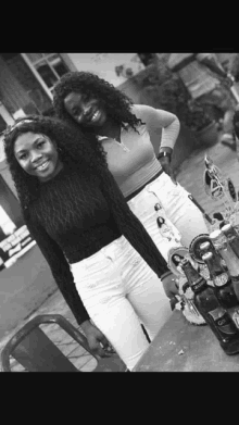 a black and white photo of two women standing next to a table with a bottle of coca cola on it