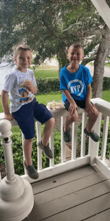 two young boys are sitting on a porch wearing shirts that say mvp