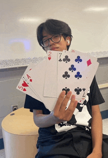 a young boy is holding a stack of playing cards including aces and queens