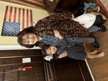 a woman holds a little girl in front of an american flag