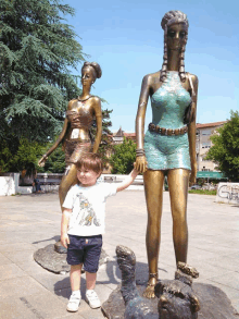 a young boy holds the hand of a statue of a woman in a short dress