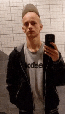 a young man is taking a picture of himself in a bathroom mirror .