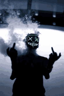 a person wearing a mask that says ' x ' on it is giving the middle finger