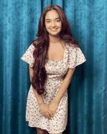 a girl with long red hair is wearing a white floral dress