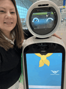 a woman stands next to a robot that says incheon airport on it