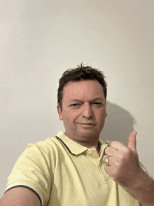 a man wearing a yellow polo shirt is giving a thumbs up