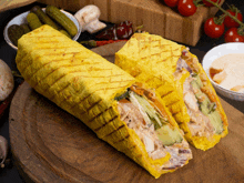 two yellow wraps with chicken and vegetables on a wooden board