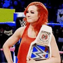 a woman with red hair is holding a blue and white wrestling belt