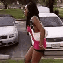 a woman in a pink dress and shorts is standing in front of a white van .